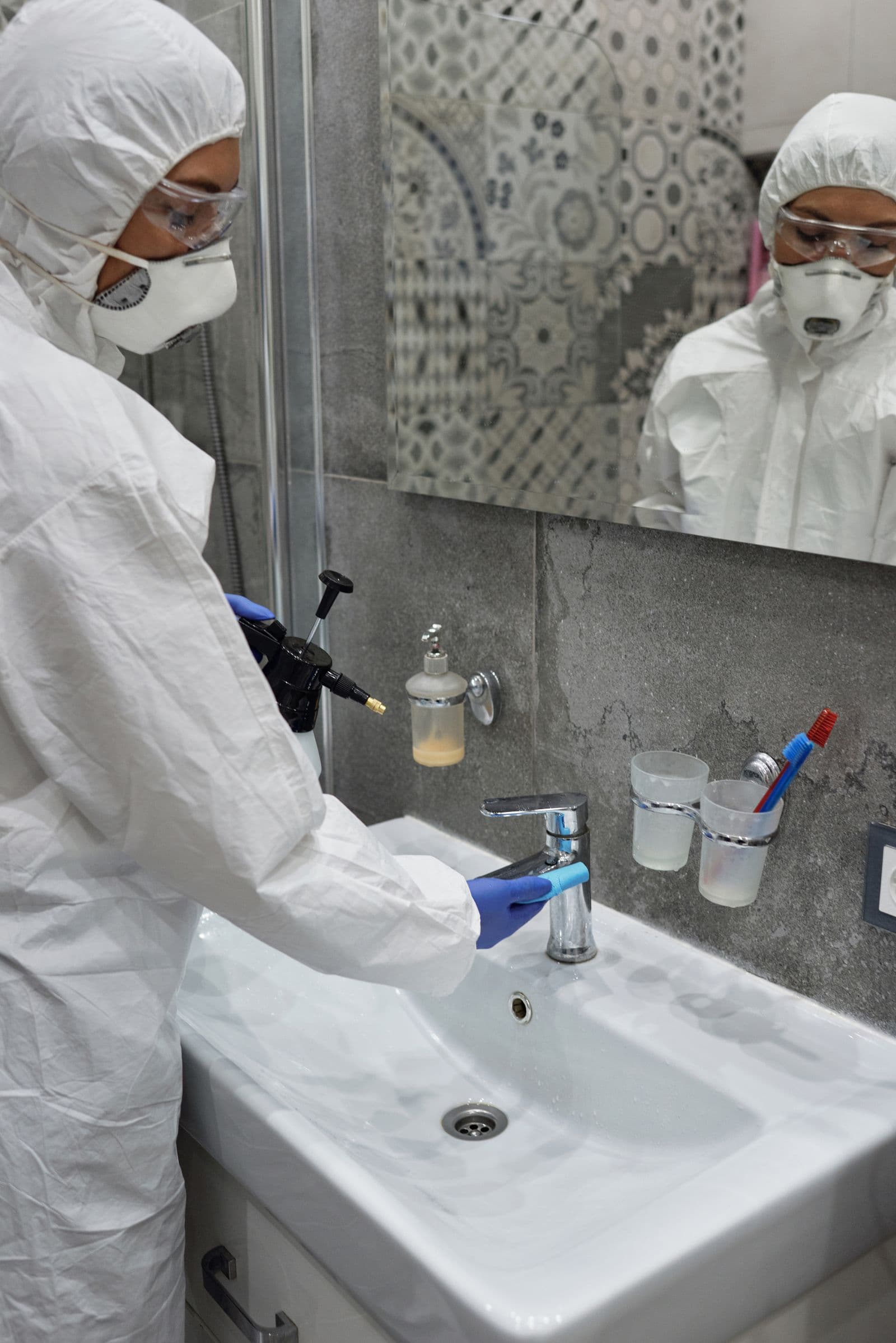 Koruyucu ekipmanlı görevli, konut banyosunda lavabo ve gider çevresine uygulama yaparken